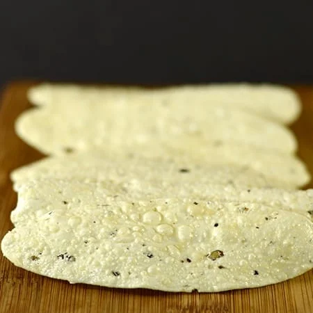 Pepper Chips - Appala Poo (100Gms) Three Thin, Roasted Indian Papads Placed On A Wooden Surface.